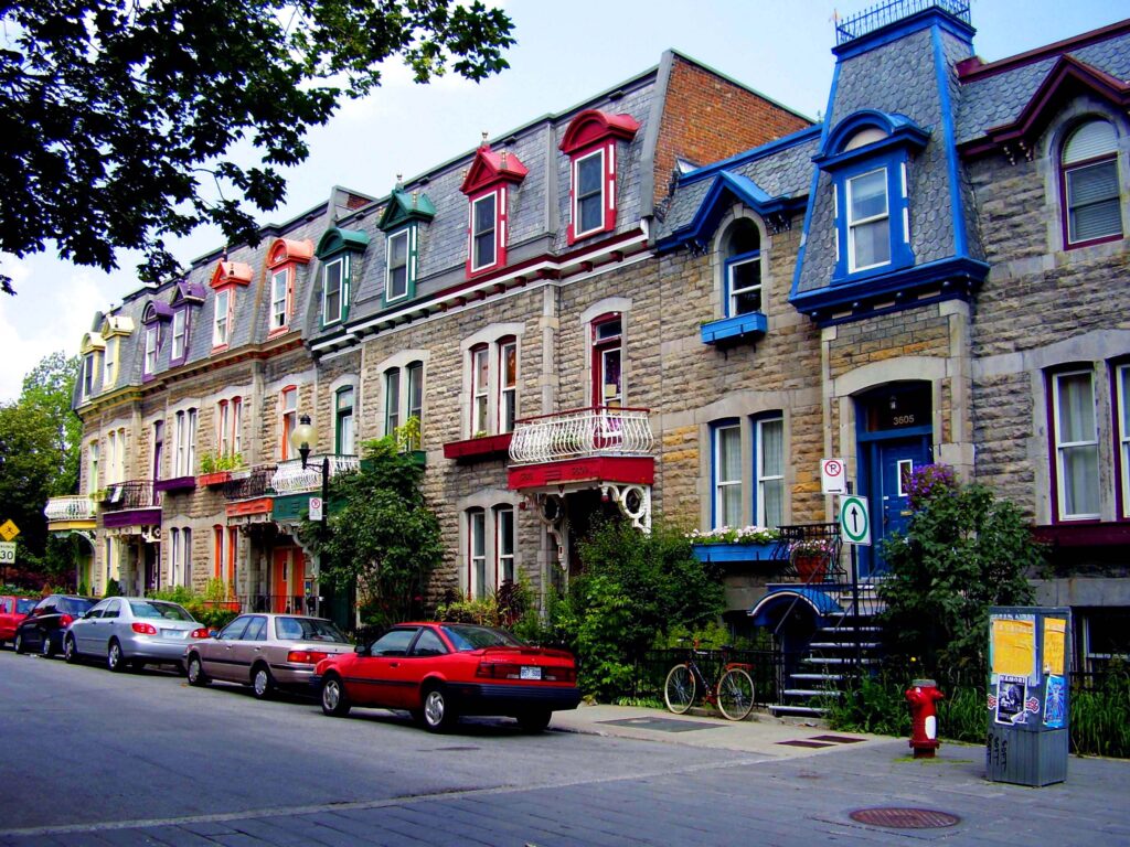 A ROW OF HOUSES WITH CARS PARKED ON THE SIDE OF THE STREET